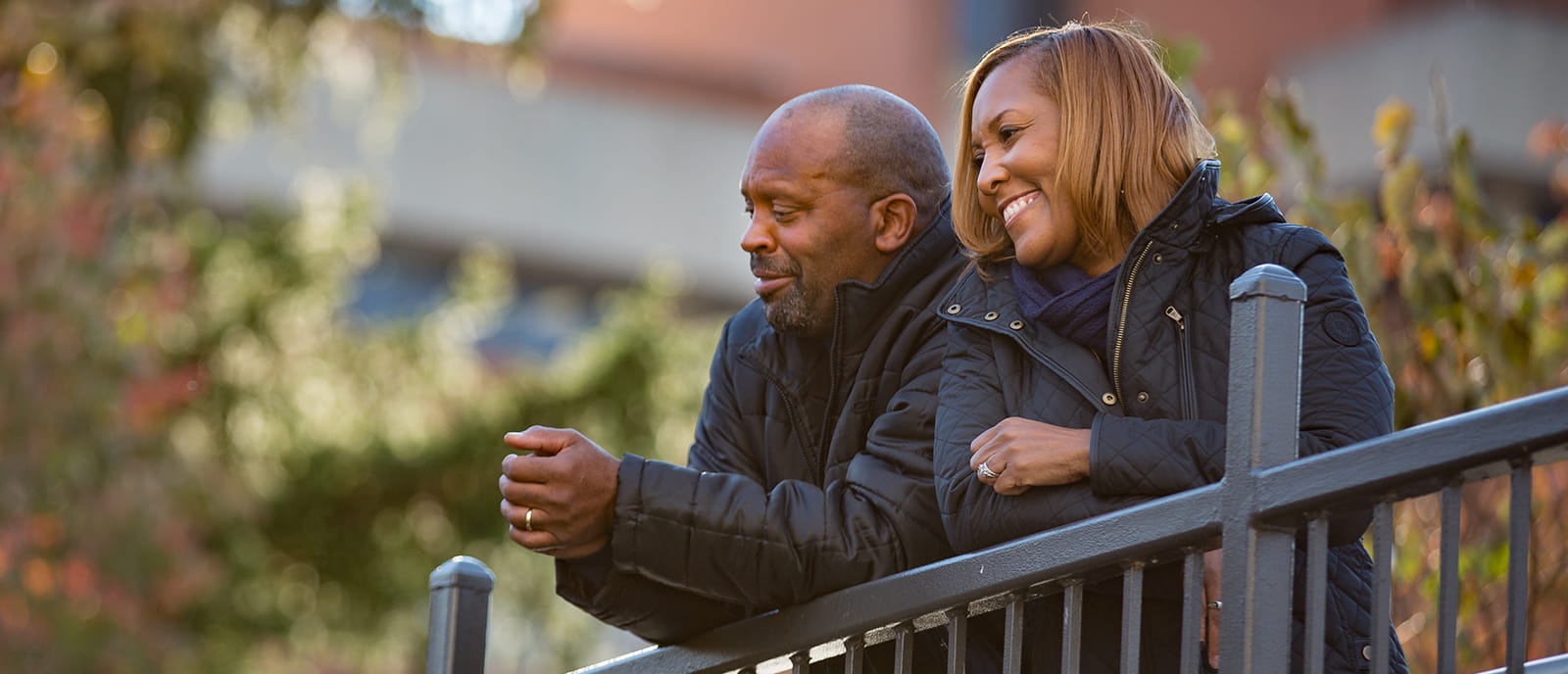image of a male and female leaning on a fence and smiling