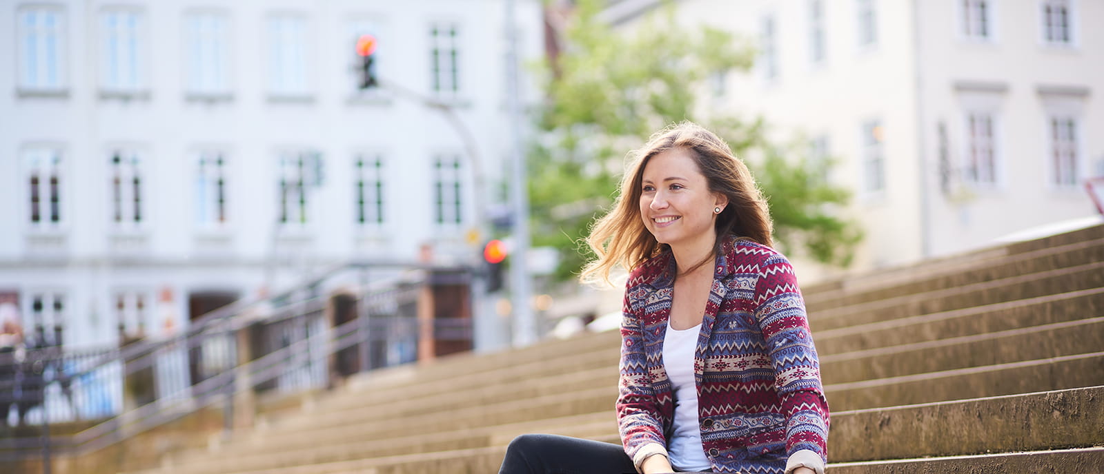 image of a young woman sitting on stairs and smiling