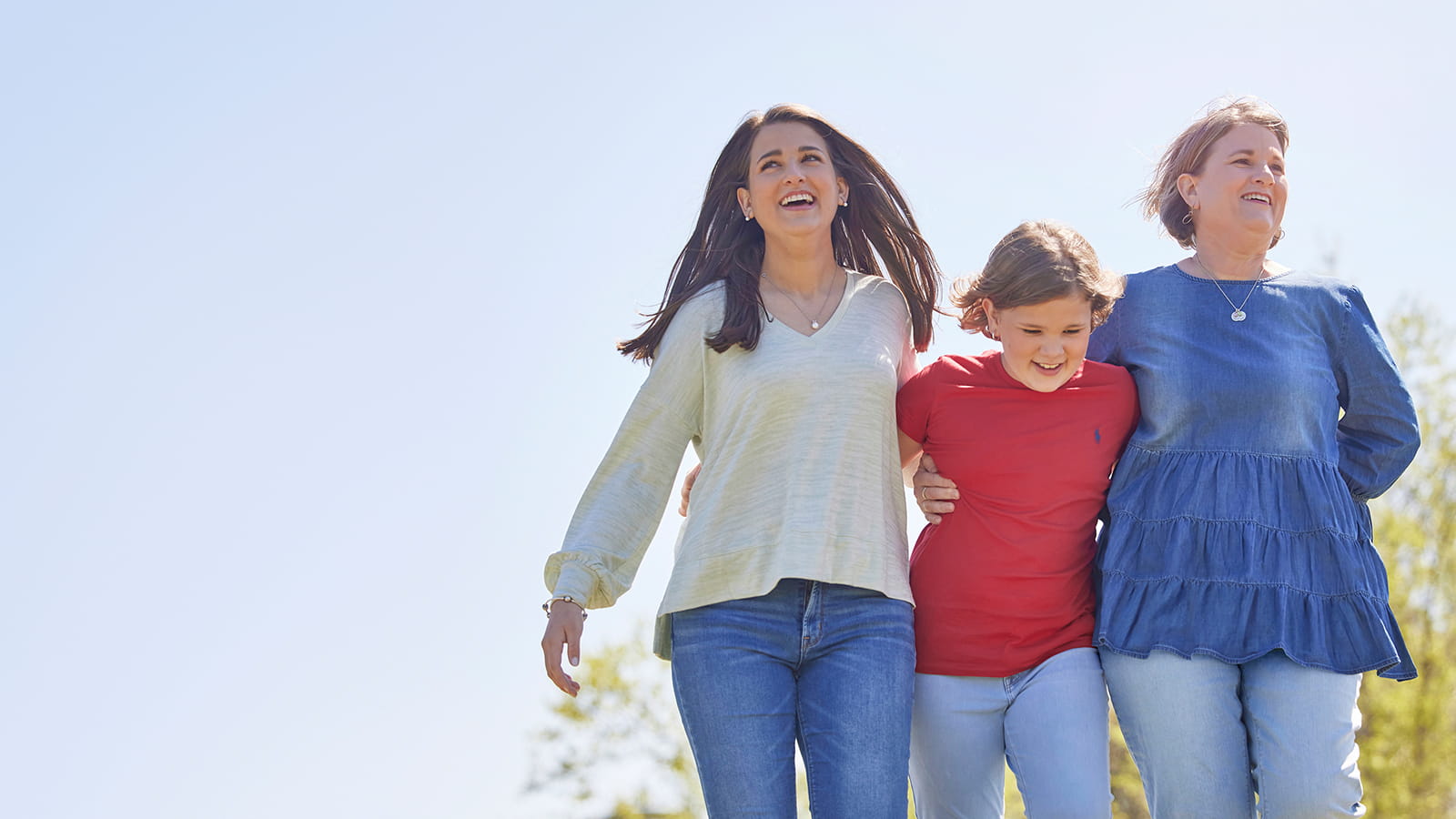 Image of three females walking happily outdoors in the sunshine