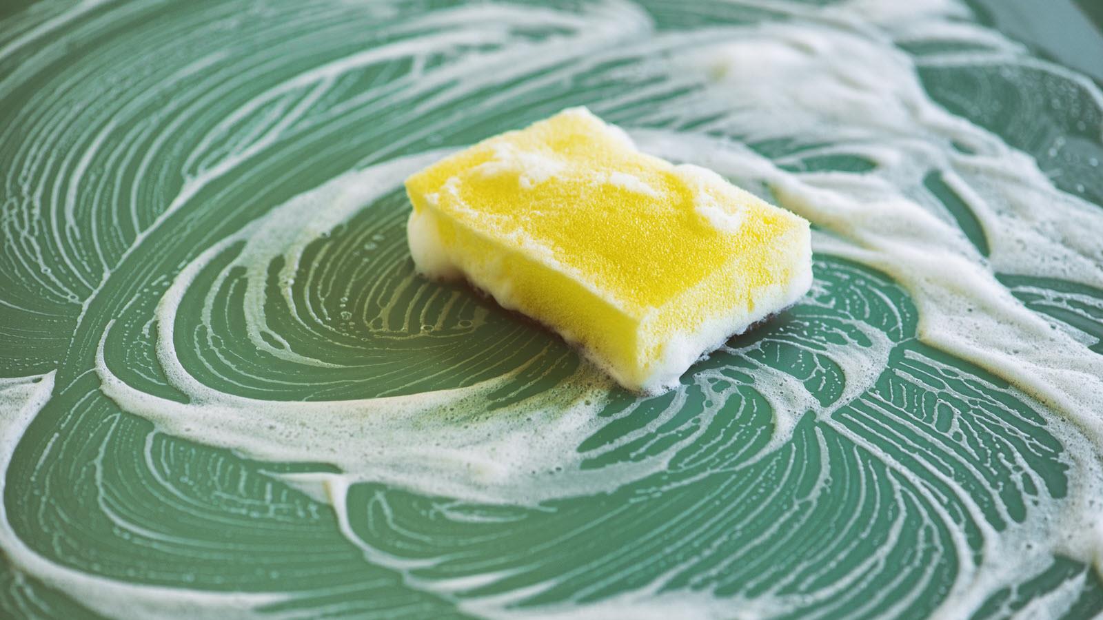 yellow sponge with suds on a green countertop