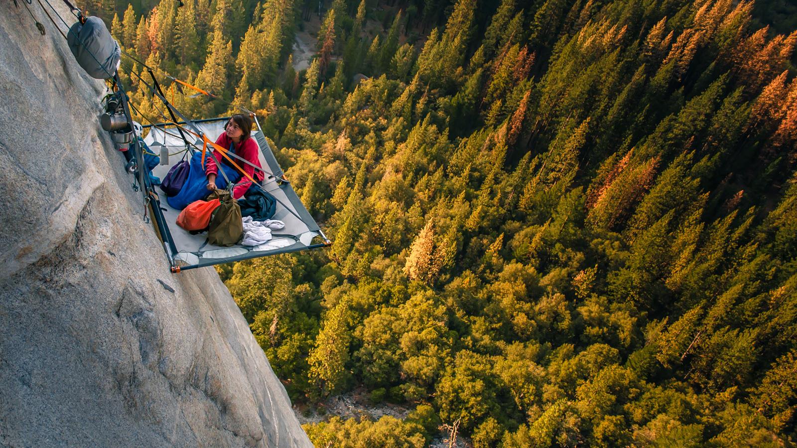 Climber takes a break from climbing hundreds of feet above the trees