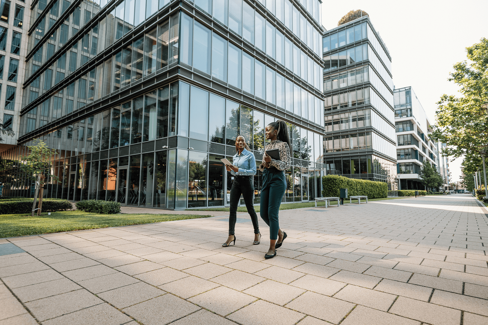 Two women walking outdoors between office buildings