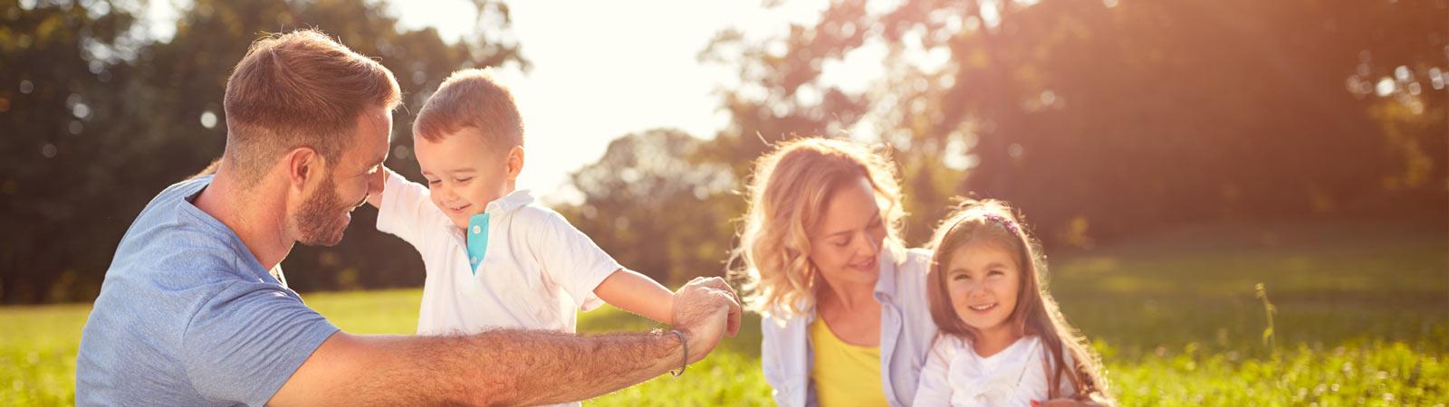A Family of four playing outdoors in the grass and sunshine