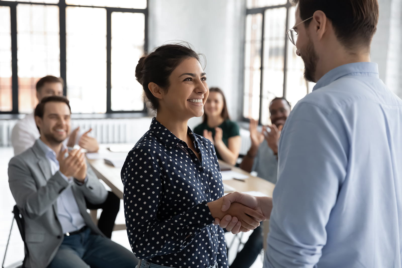 Image of work colleagues shaking hands in an office and smiling