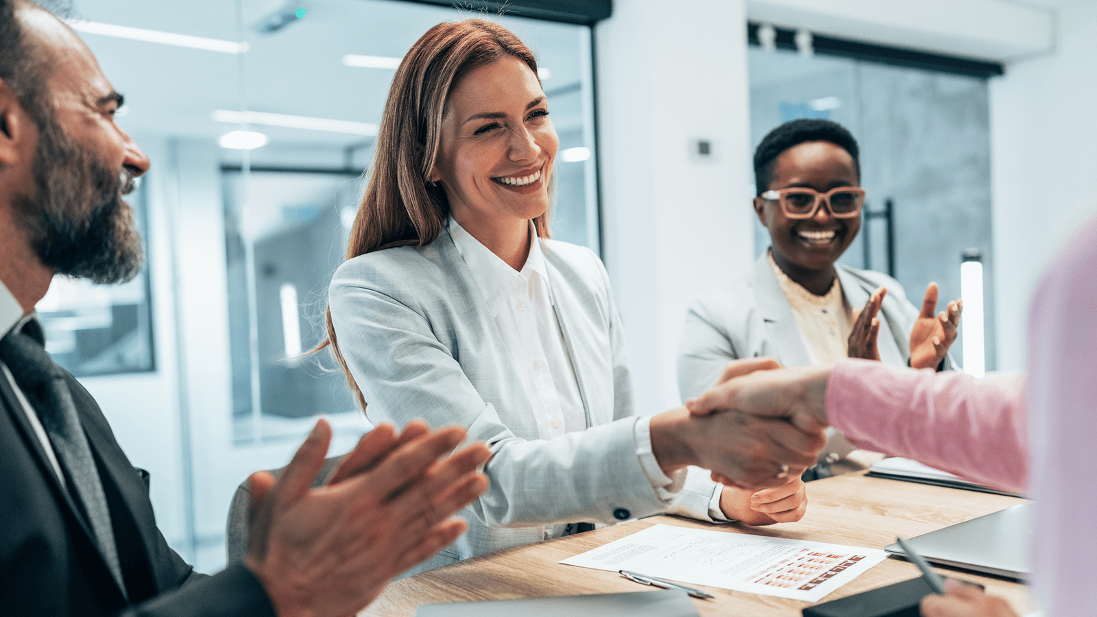 Happy people in a meeting room, shaking hands and clapping