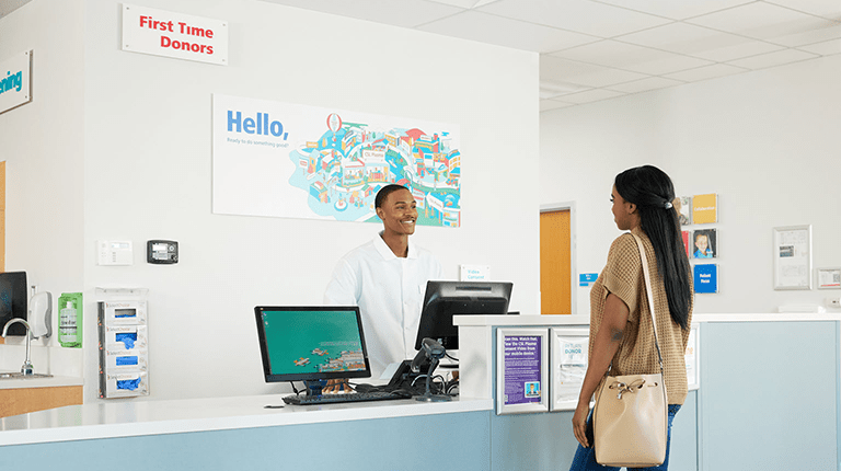 Photo of a female donor speaking with a CSL Plasma receptionist at a CSL Plasma Center