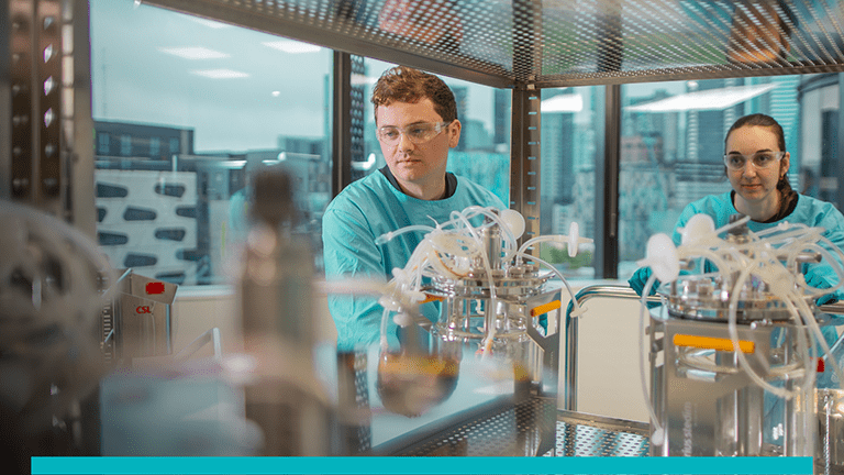 Picture of two scientists in green lab attire in a laboratory