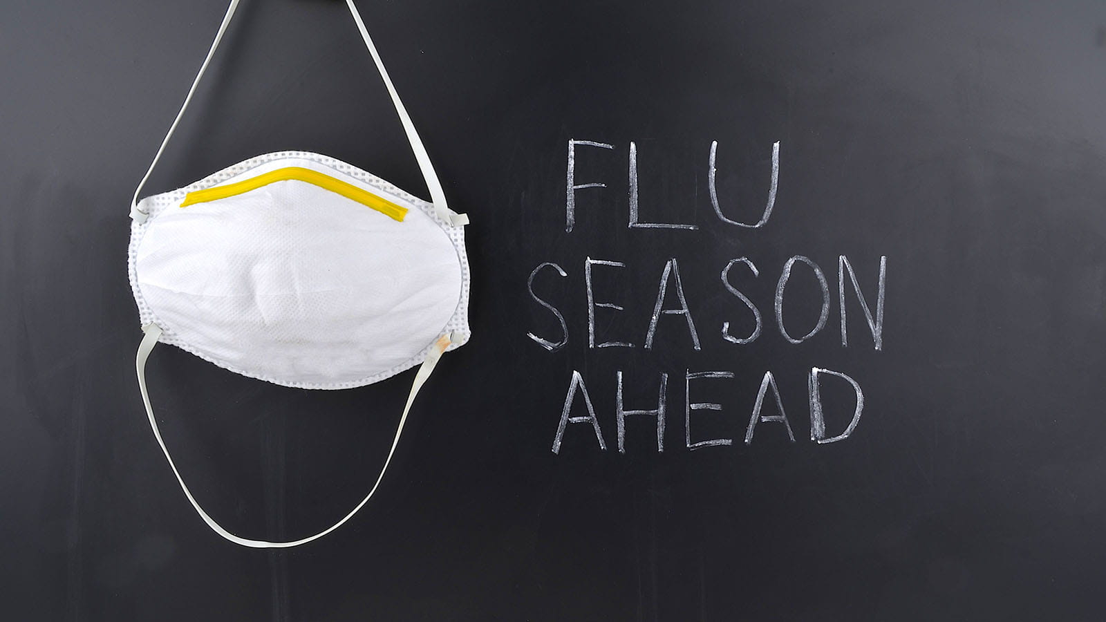 Chalkboard reads 'Flu Season Ahead' next to a mask.
