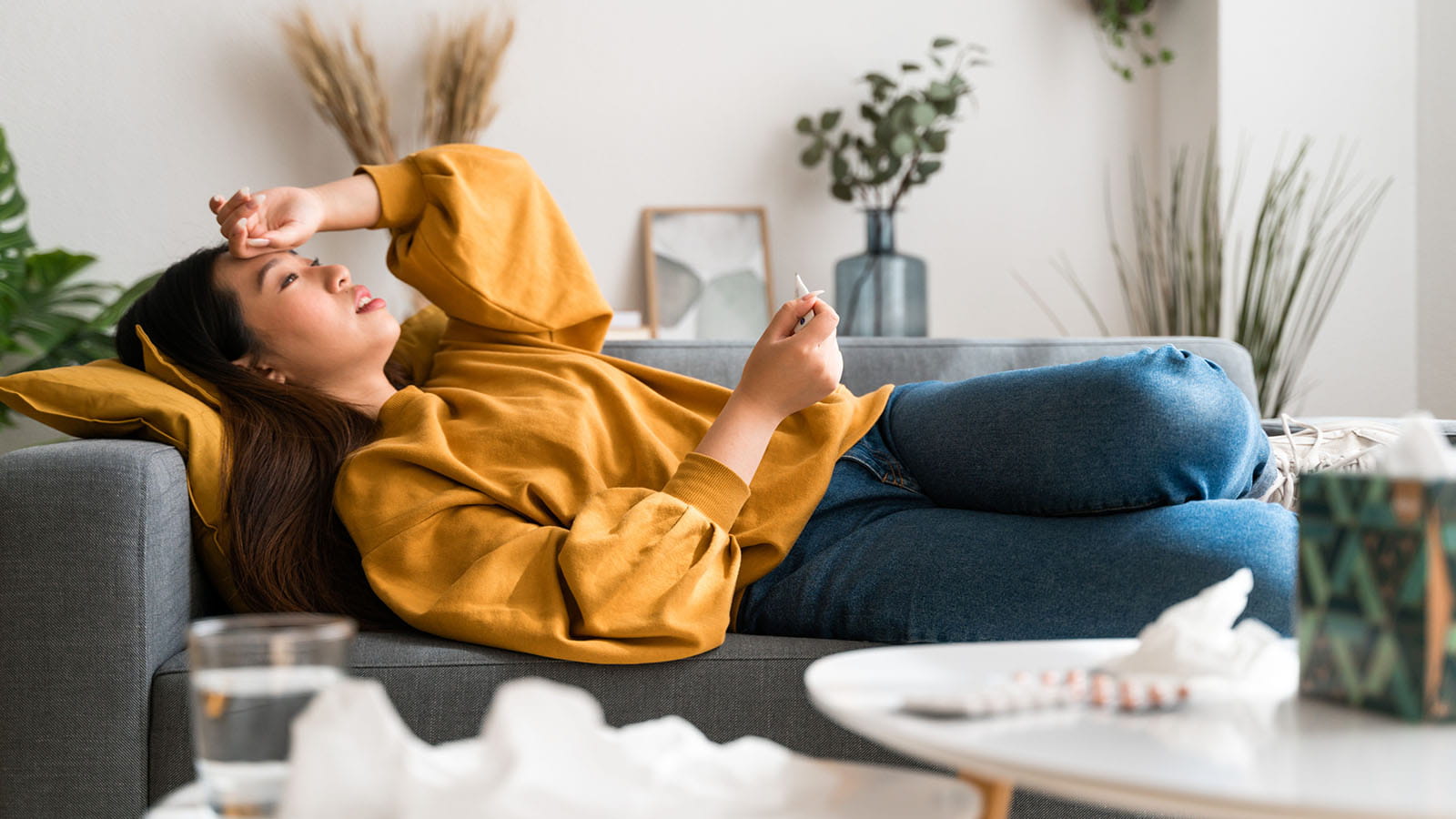 Woman sick with flu rests on her couch.