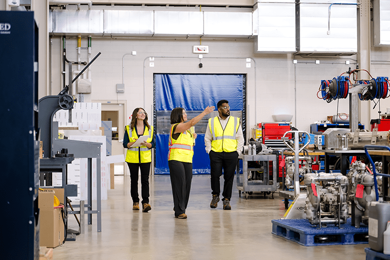 colleauges walking through a warehouse wearing high visibility safety vests
