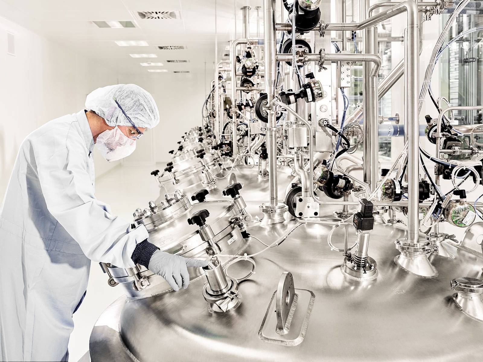 Gowned employee looking into a tank