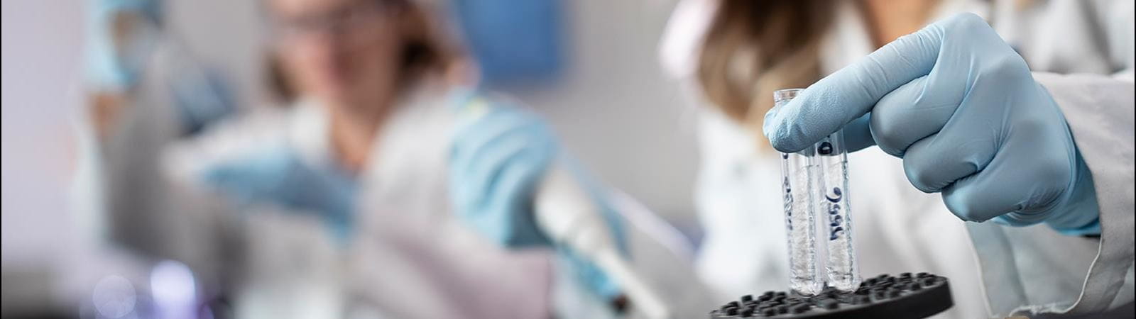 Two female researchers testing vials in a lab