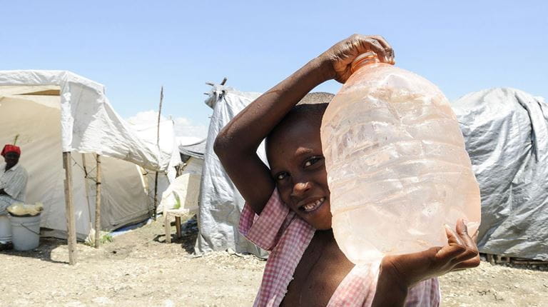 Disaster relief young child holding large water bottle in a refuge camp