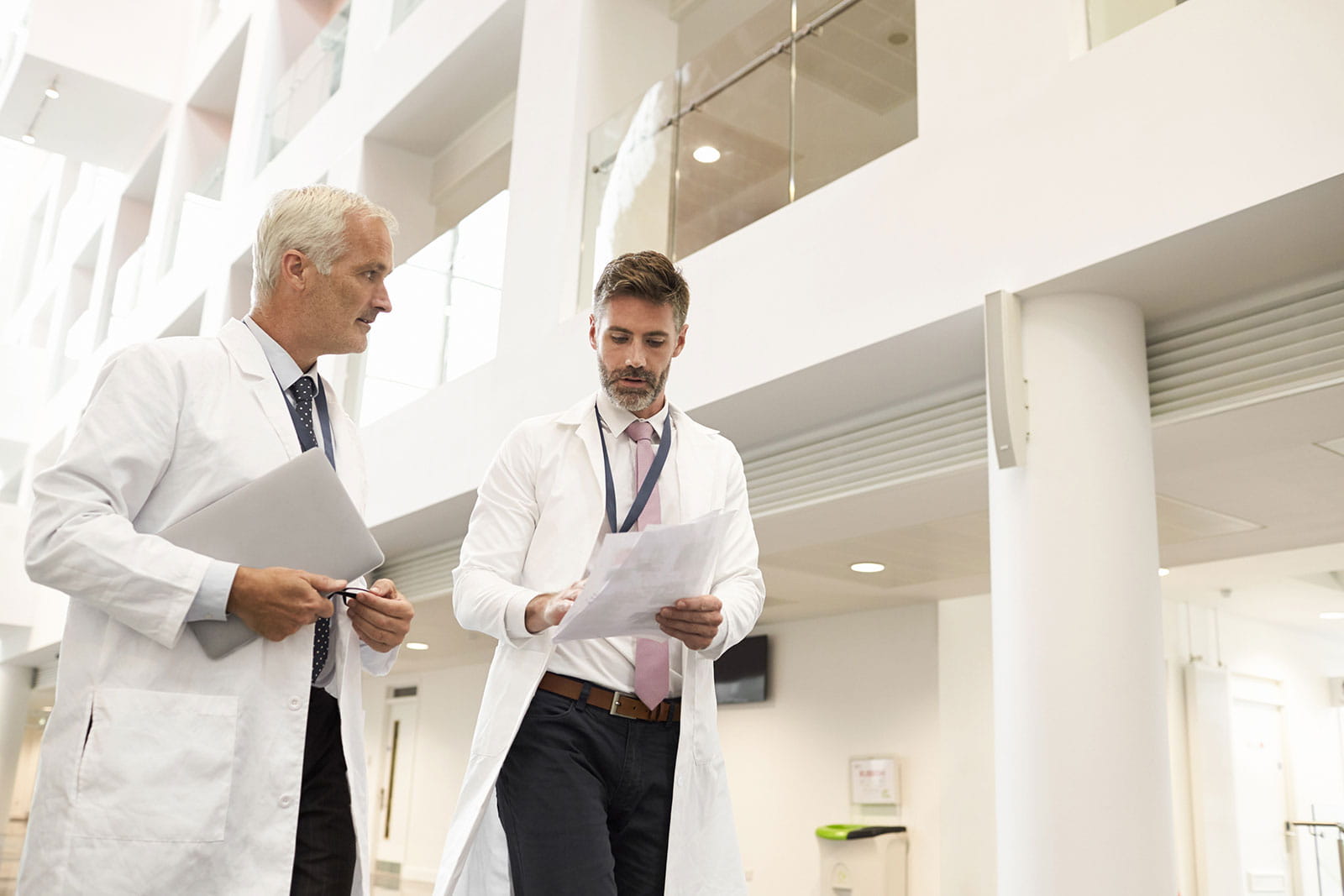Two people in white lab coats walking and talking