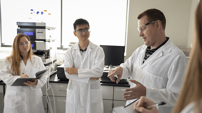 Three scientists walking in a laboratory setting