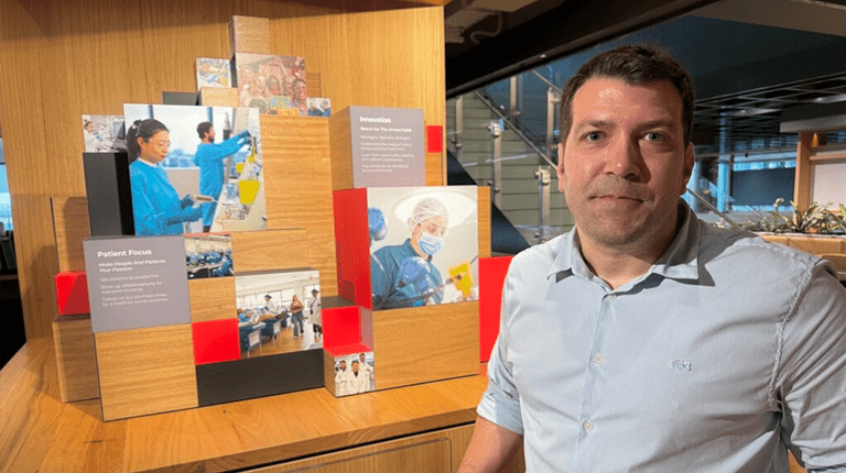 Photography of Alberto in an office environment standing in front of a display