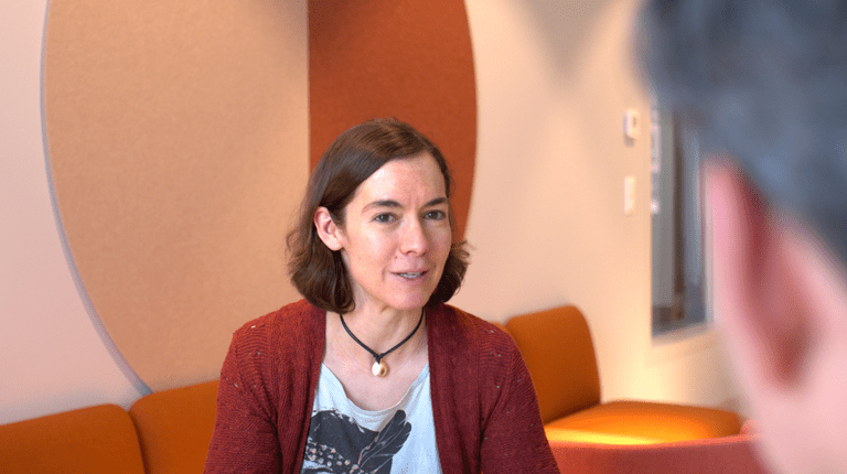 Photograph of lady in a meeting taking place in an office environment.