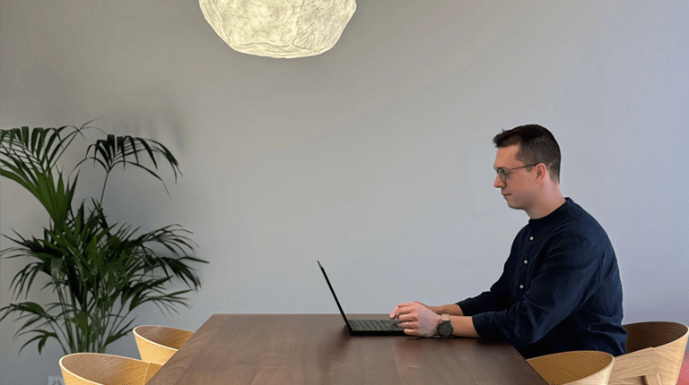 Photography of Christopher in an office environment sitting at a desk typing on a laptop computer
