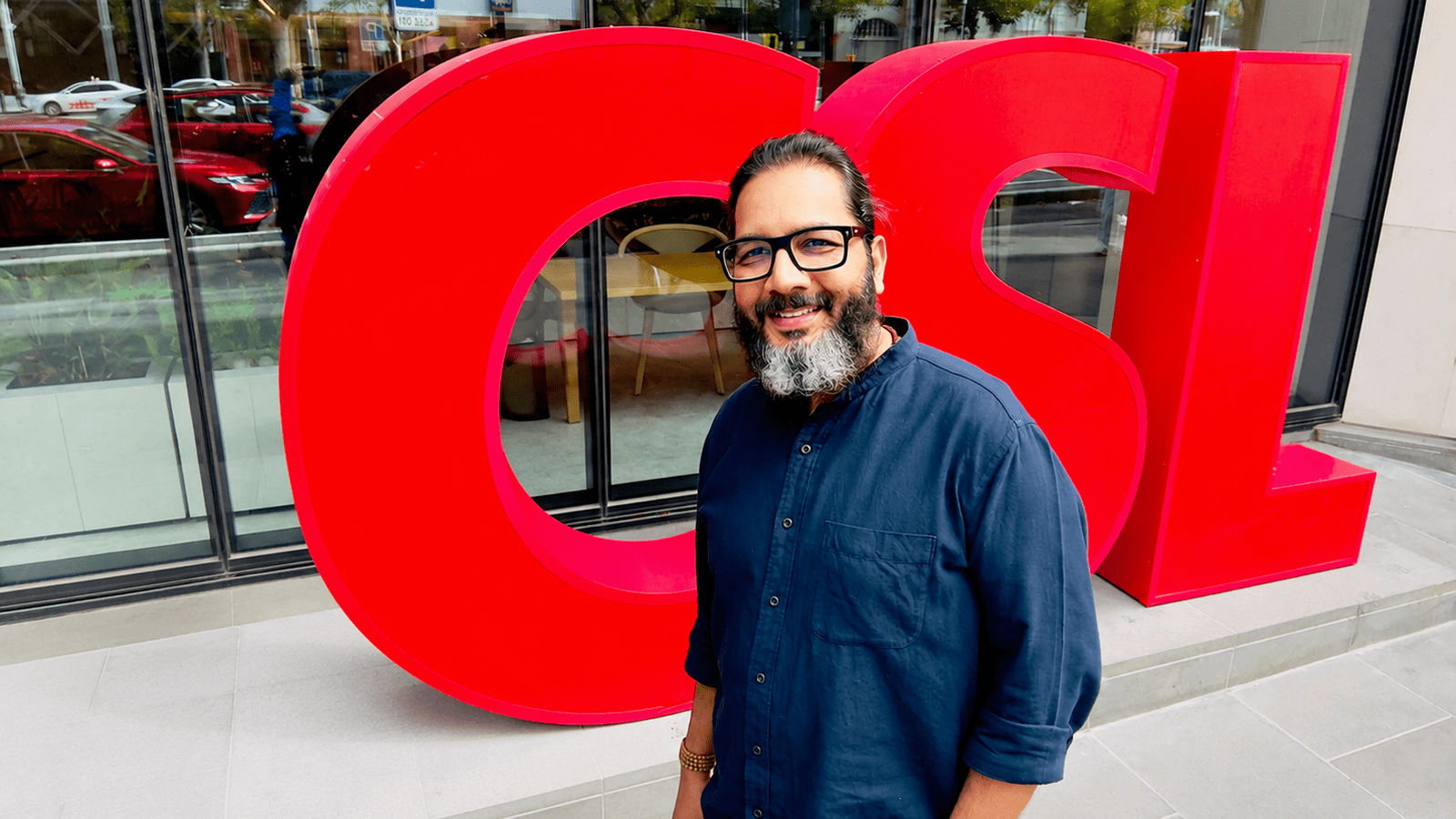 Photograph of Sunil Kumar Raja standing in front of a 'CSL' sign out the front of the CSL Melbourne Office Building