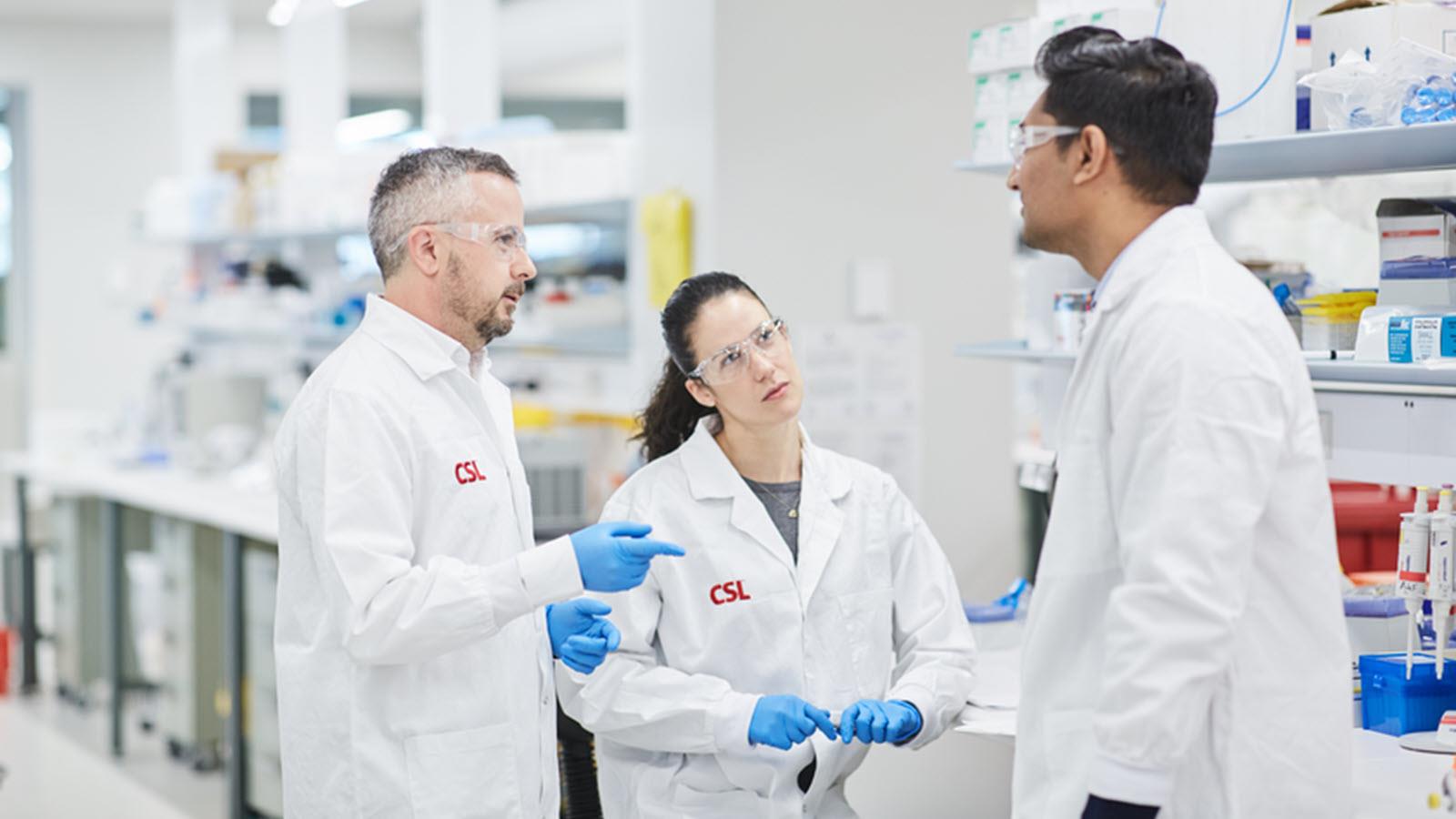 Two male and one female scientist talk in a lab environment