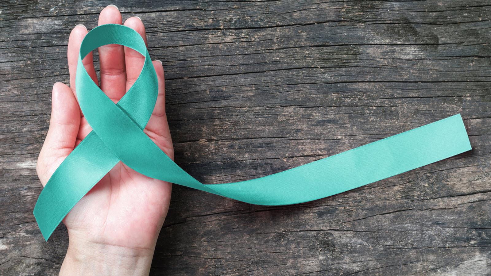 Hand holding a teal ribbon signifying scleroderma