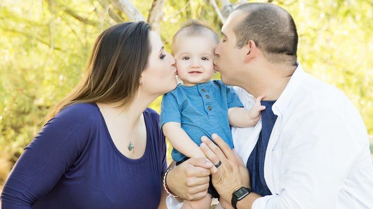 Terry Young and his wife both kiss their infant son on the cheek