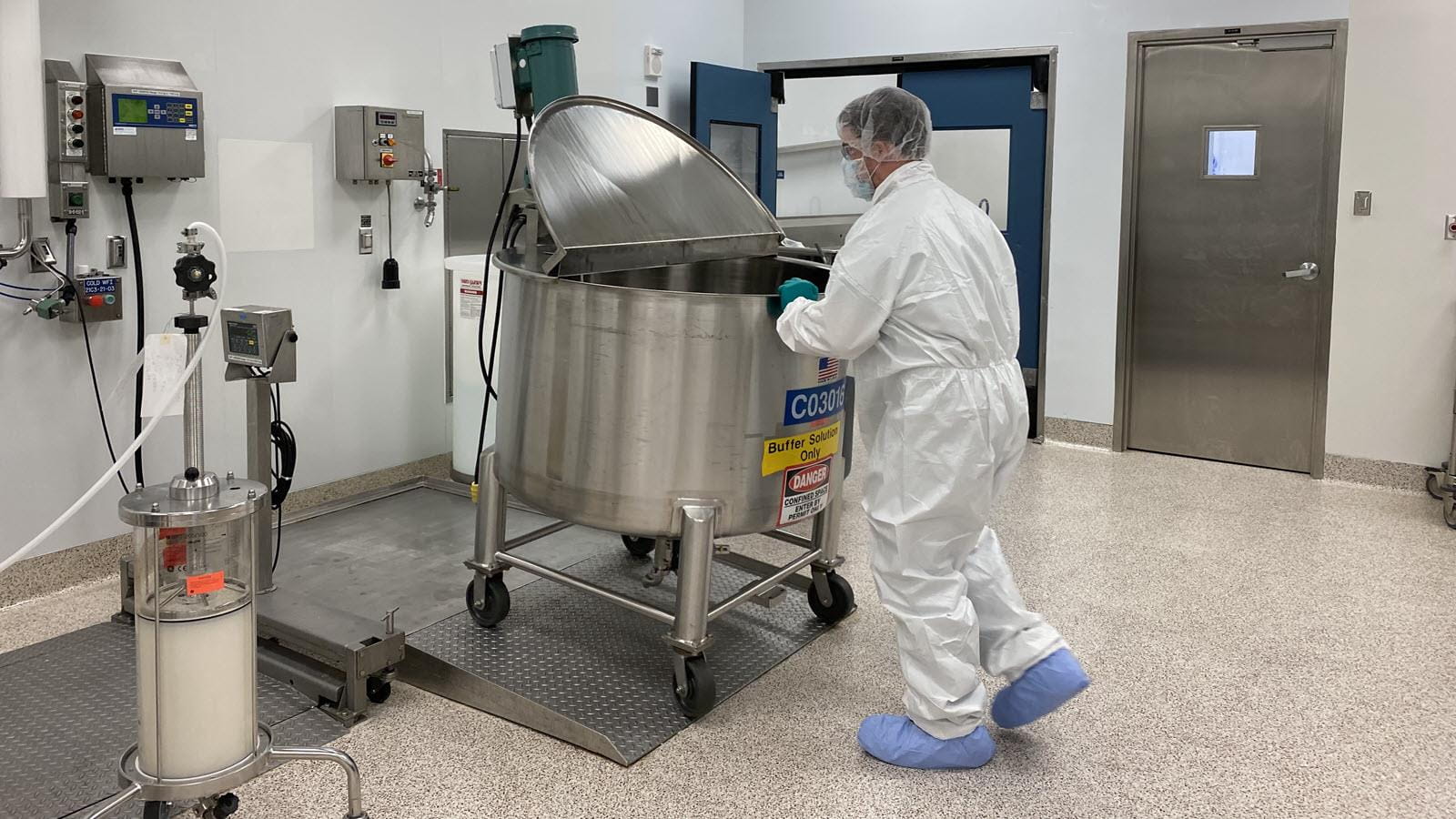 A worker in mask and gown inside CSL Behring's pilot plant in Kankakee, Illinois.