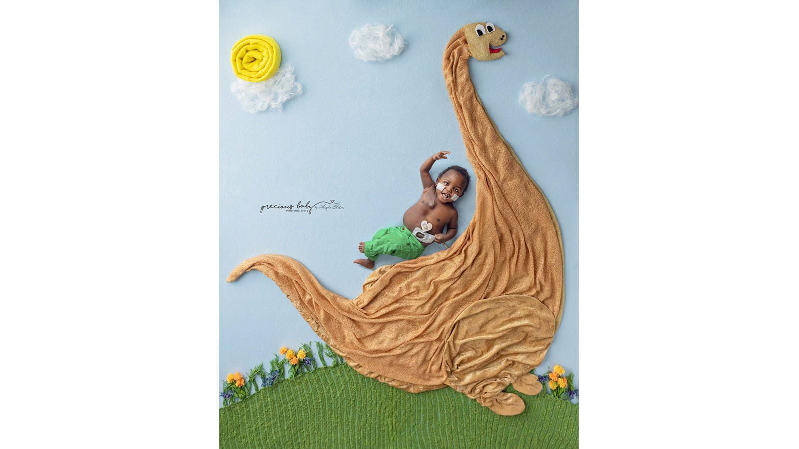 Baby happily rides the back of a pretend dinosaur