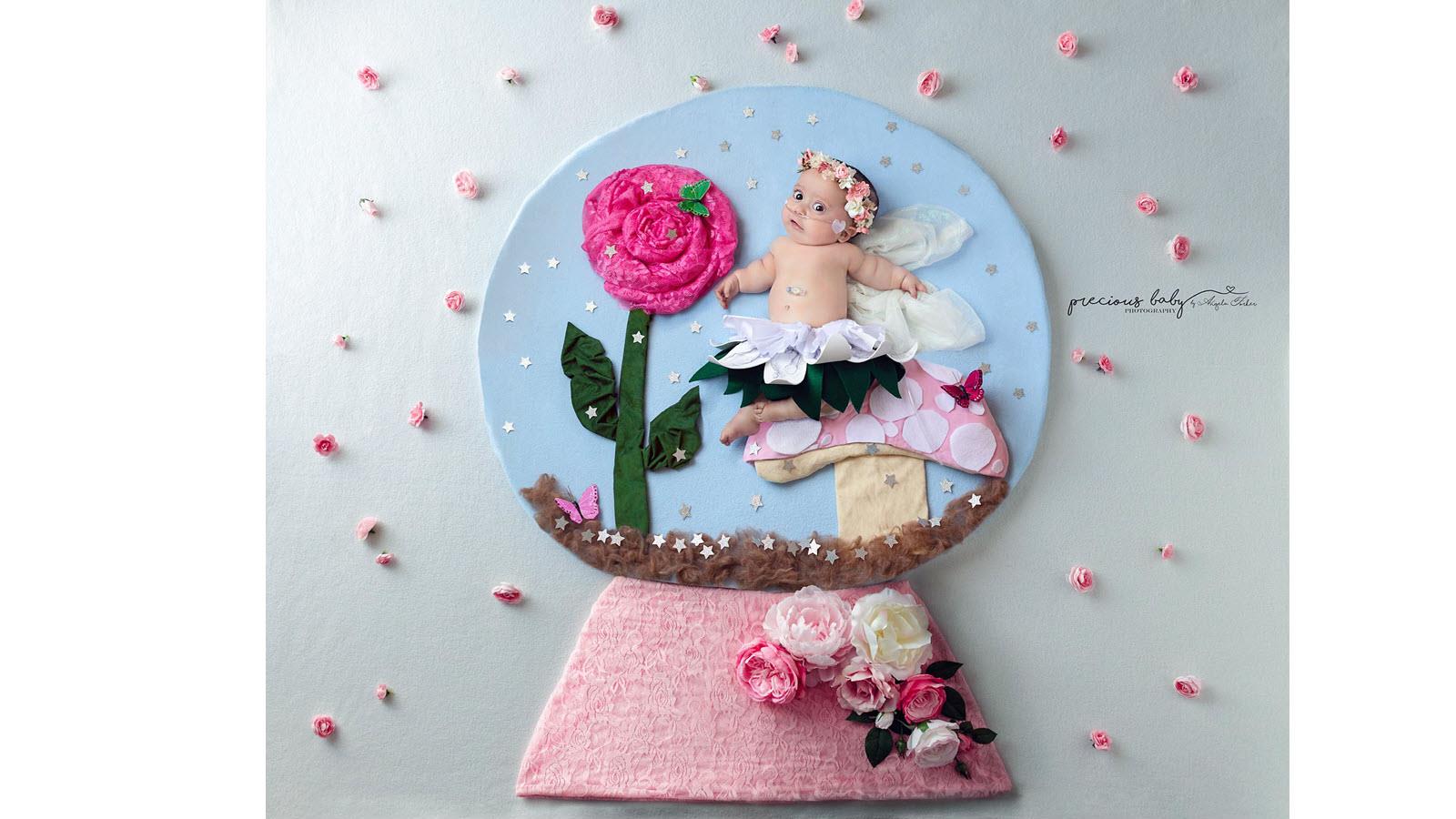 Baby dressed as a fairy wears a floral crown inside a snow globe scene