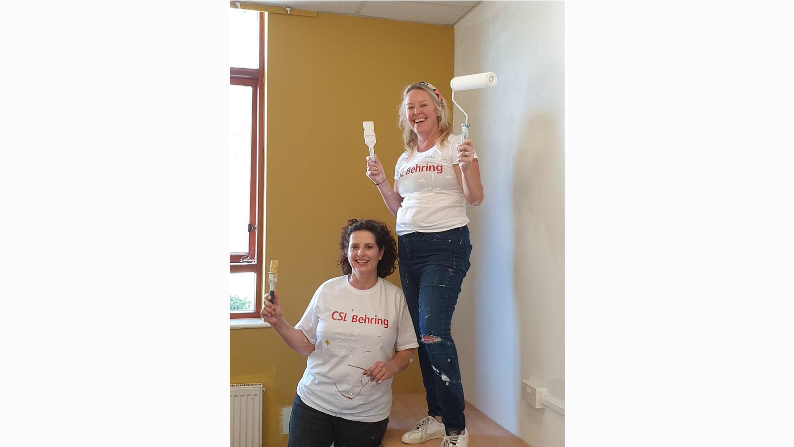 two employees painting while wearing CSL Behring t-shirts