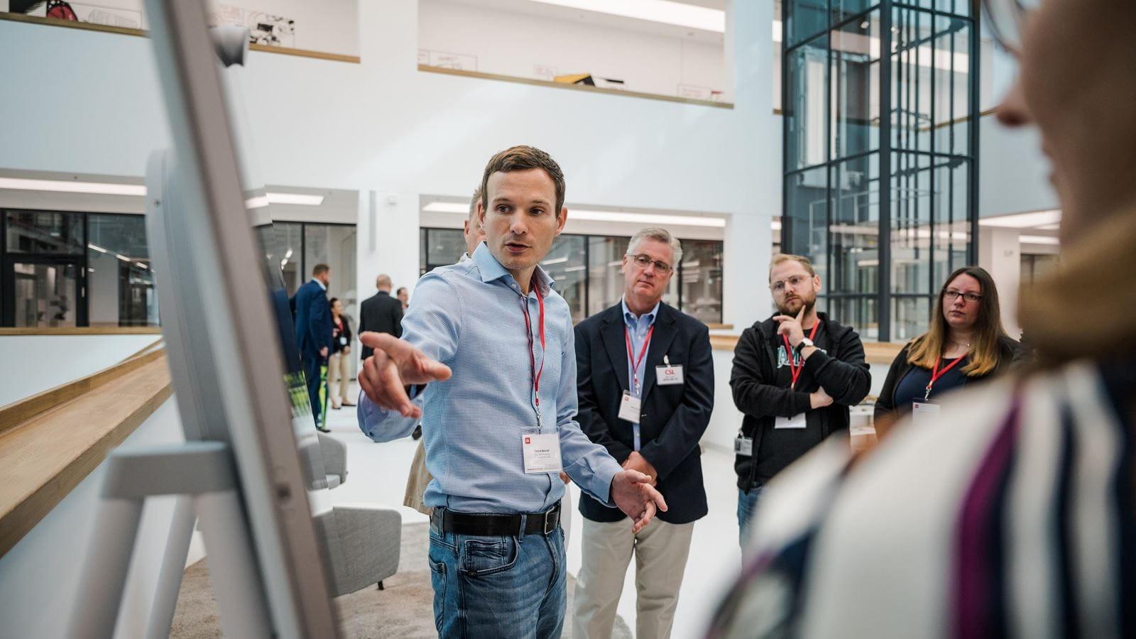 A tour guide explains the M600 R&D building to a group during the launch event.