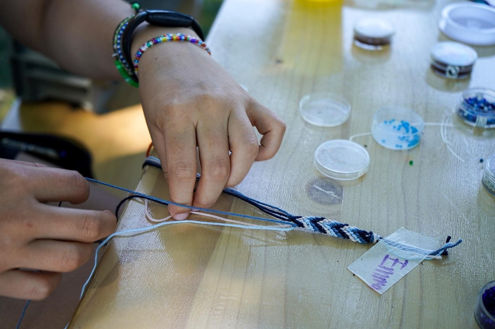A child works on beading a bracelet.