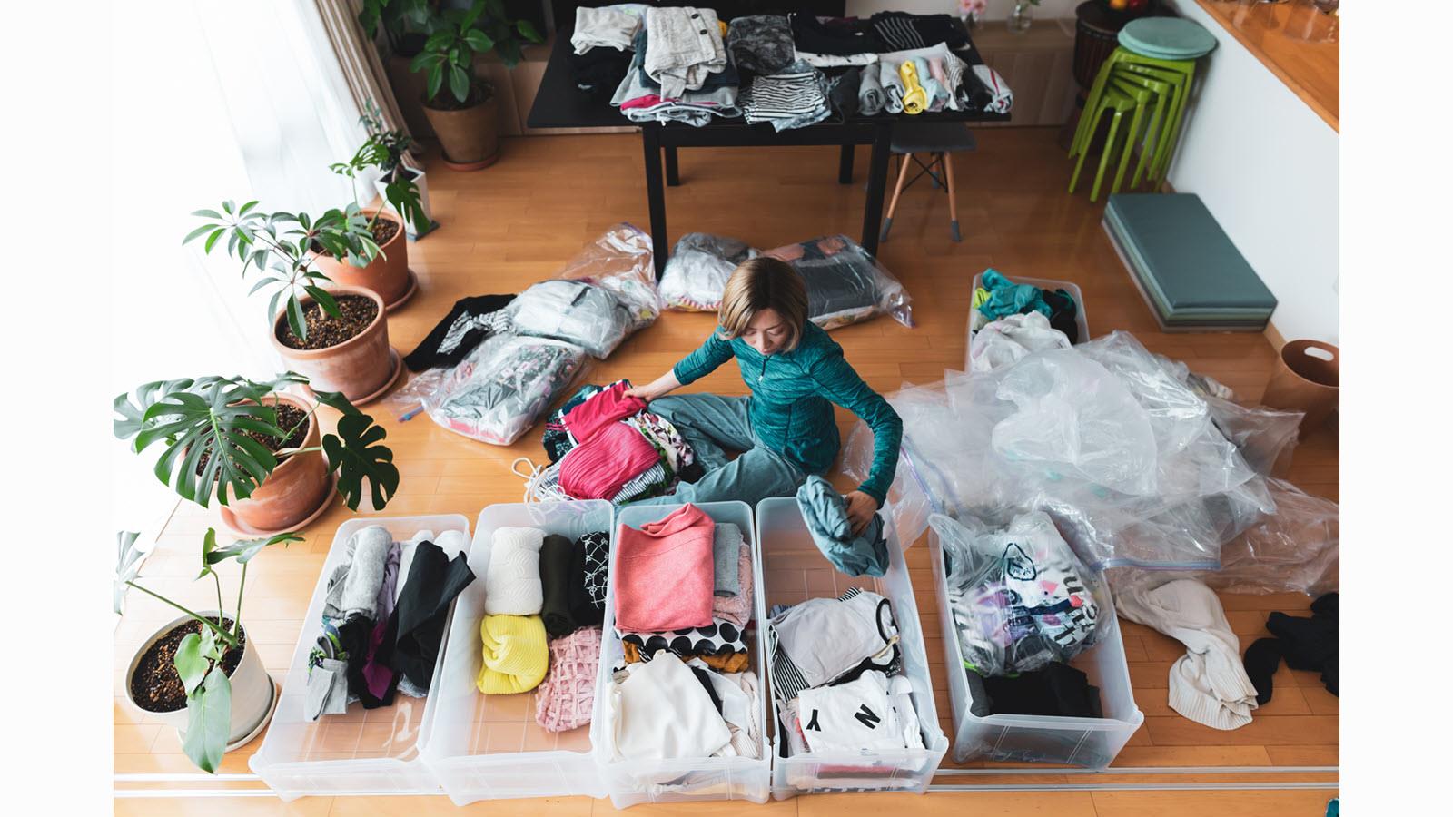 woman sorts clothes into plastic bins