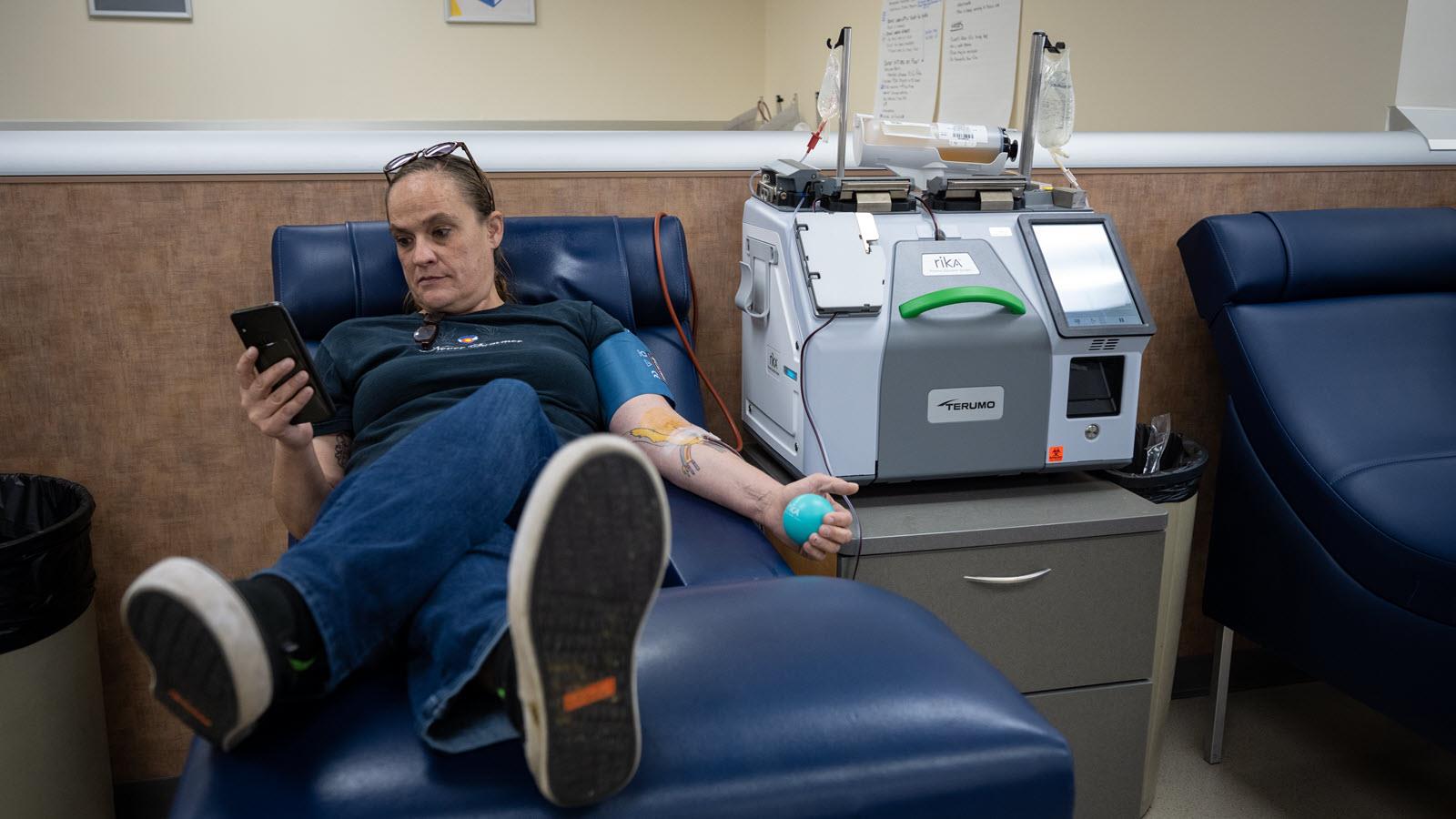 Kelly Geiser looks at her phone while donating plasma at a CSL Plasma Center.