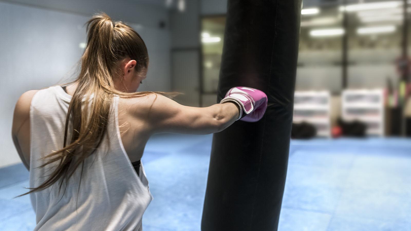A female boxer with a ponytail works out with a punching bag