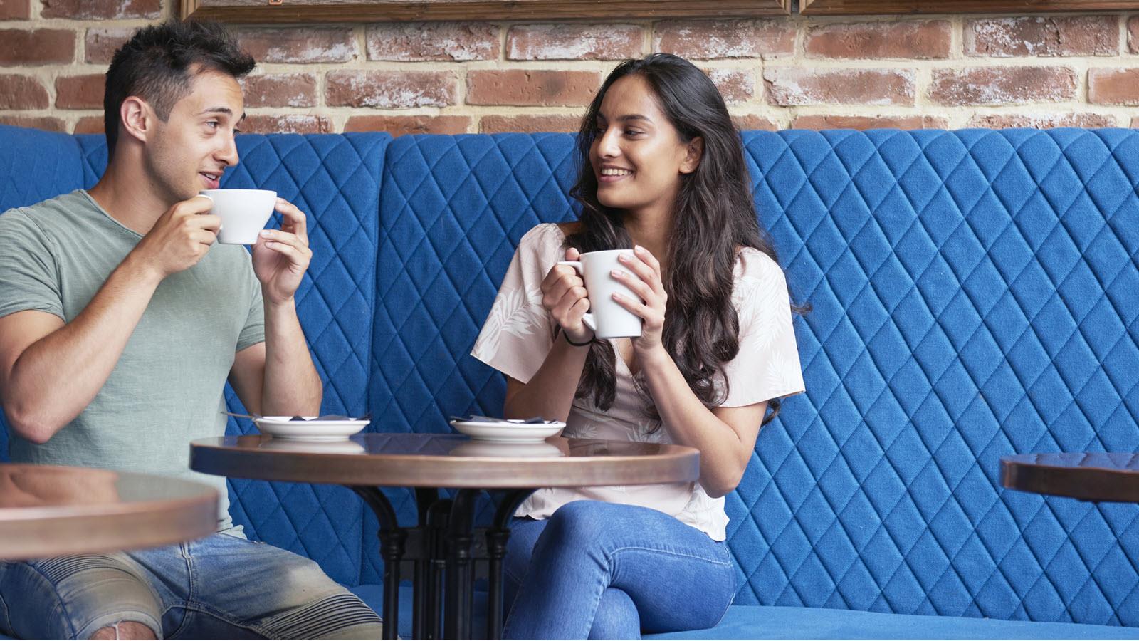 young couple drinks coffee in a cafe on a blue couch