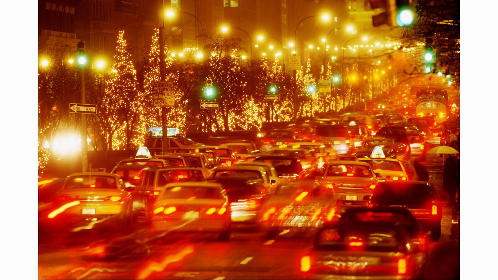 heavy traffic at night with lighted Christmas trees along the street