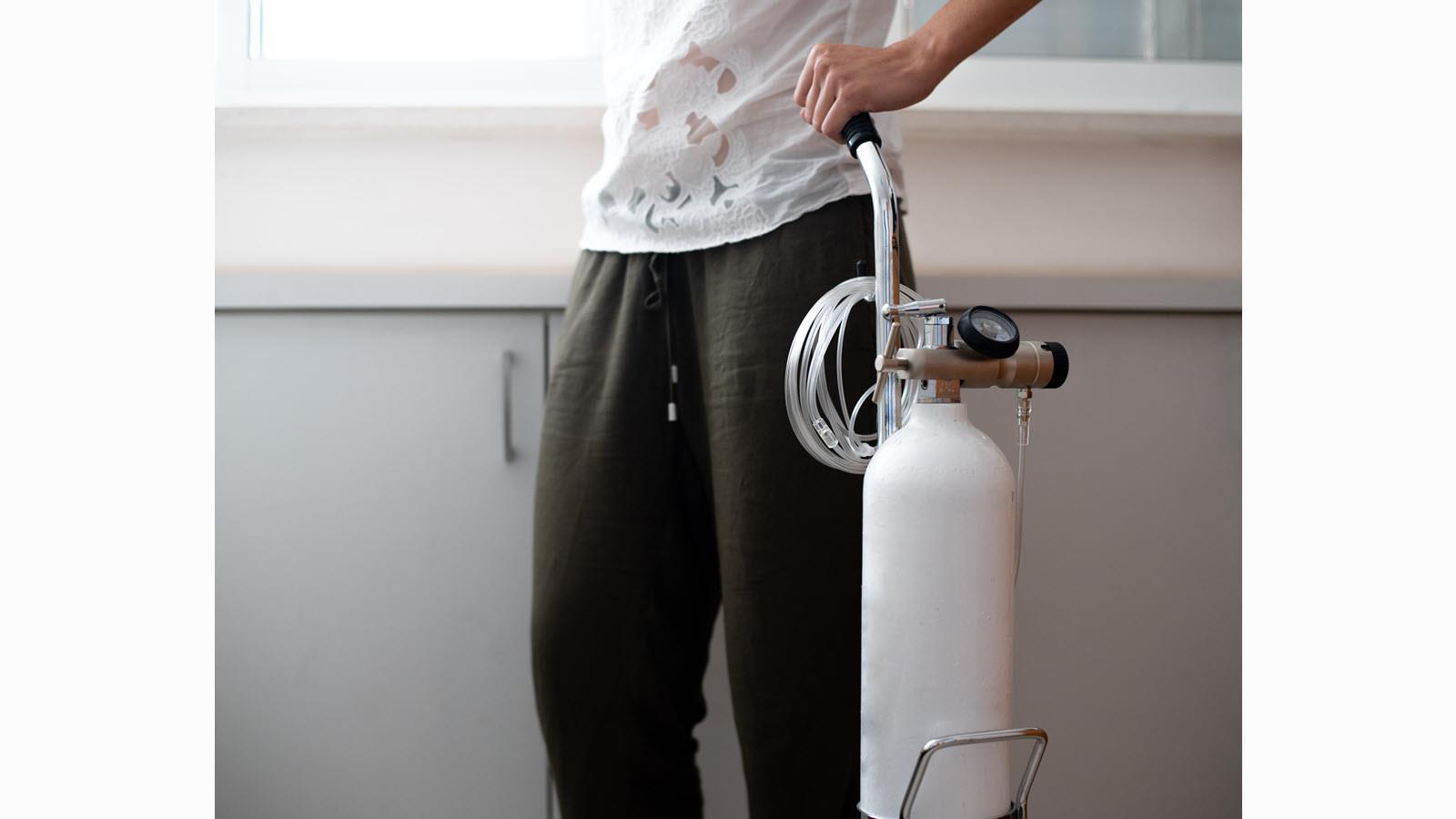 person standing with a portable oxygen tank