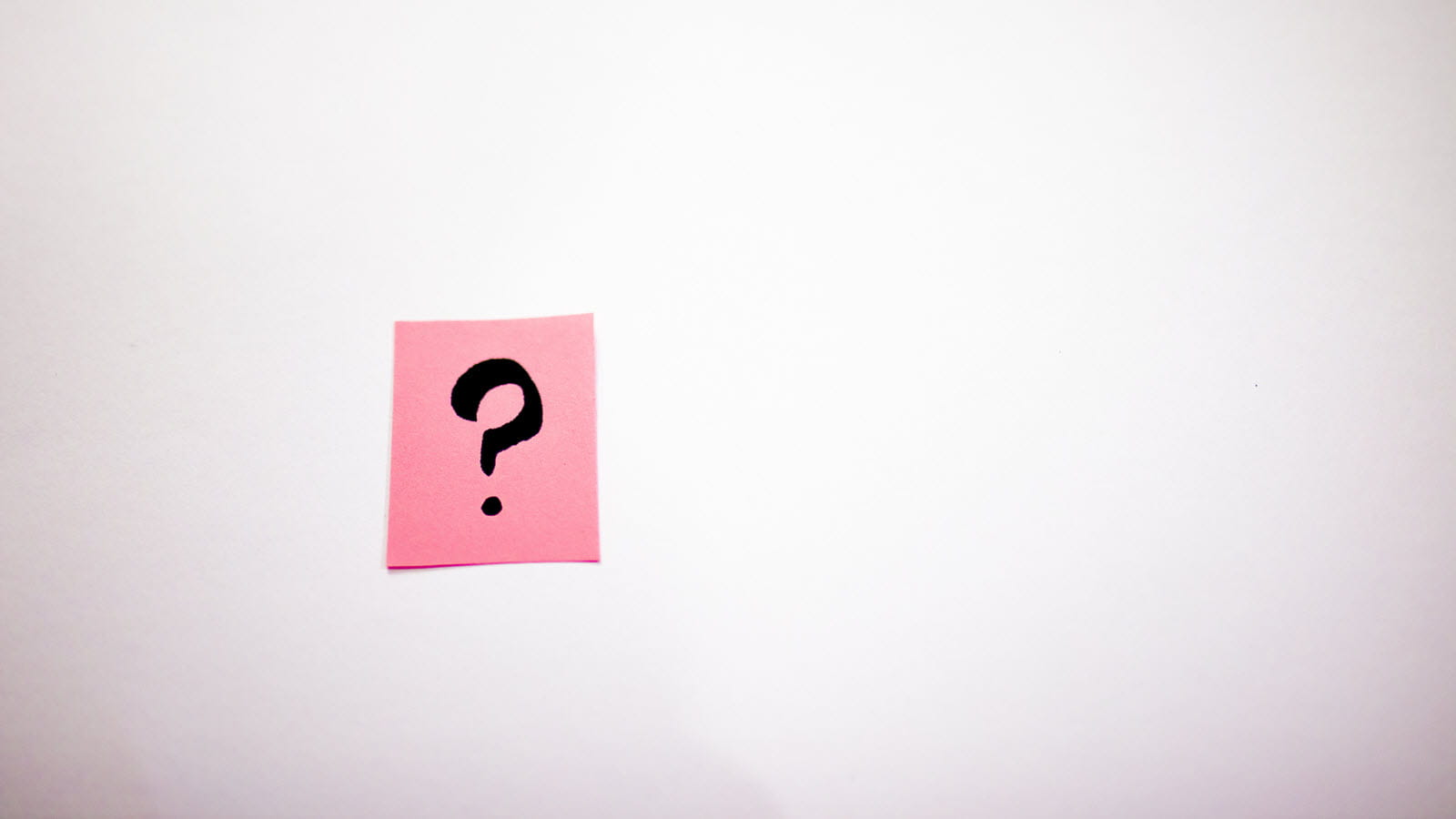 Black question mark on a pink sticky note