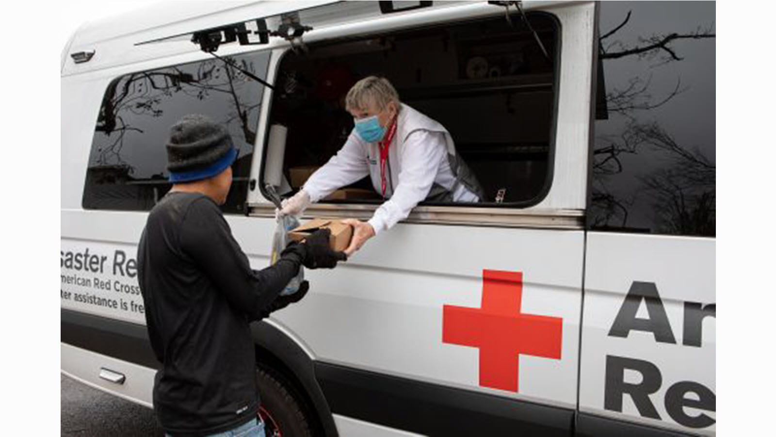 Red Cross worker hands a boxed meal to a disaster victim.