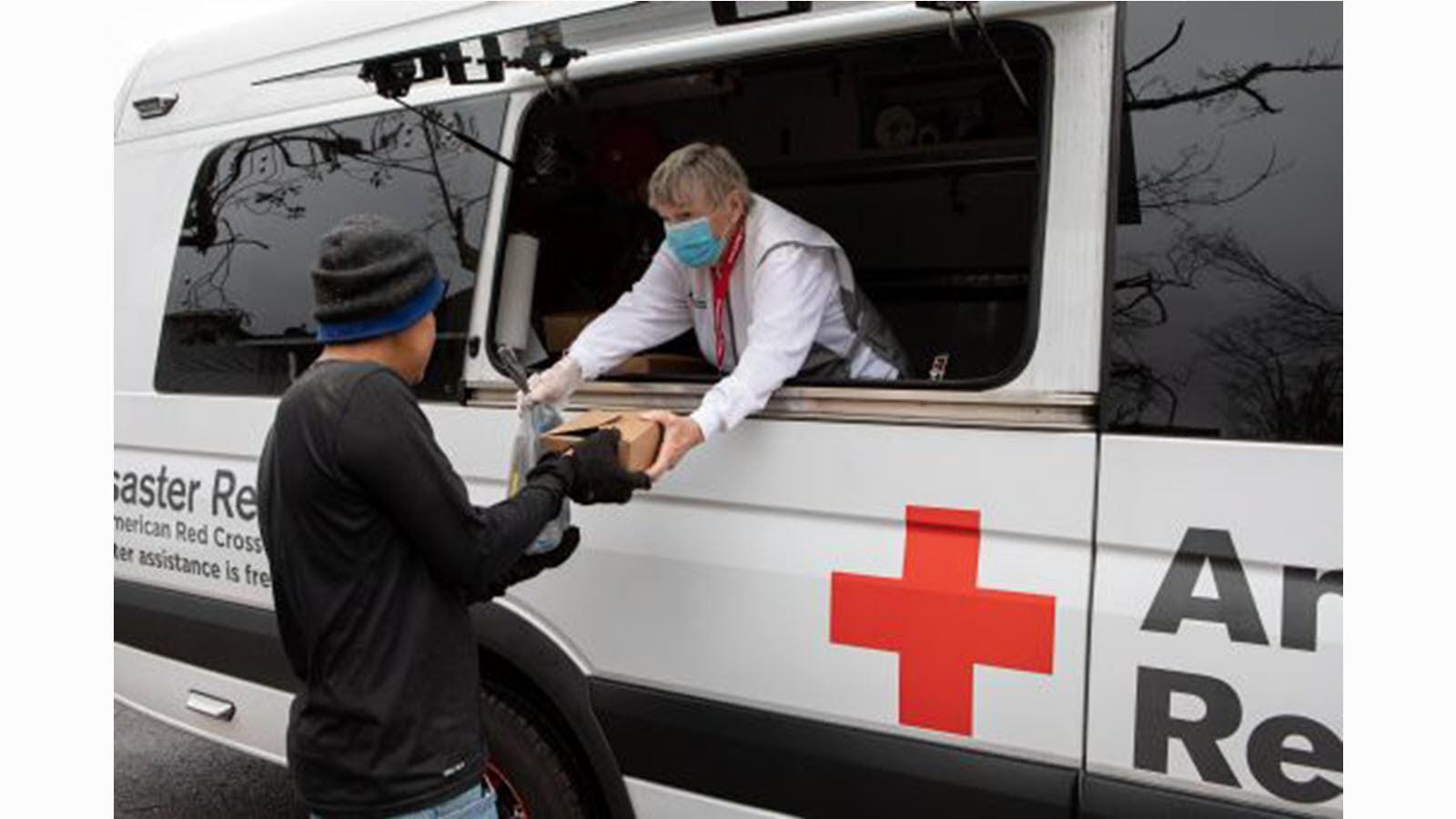 Red Cross worker hands a boxed meal to a disaster victim.