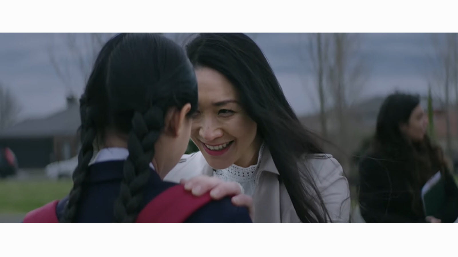 Mother smiles at young daughter who has braids