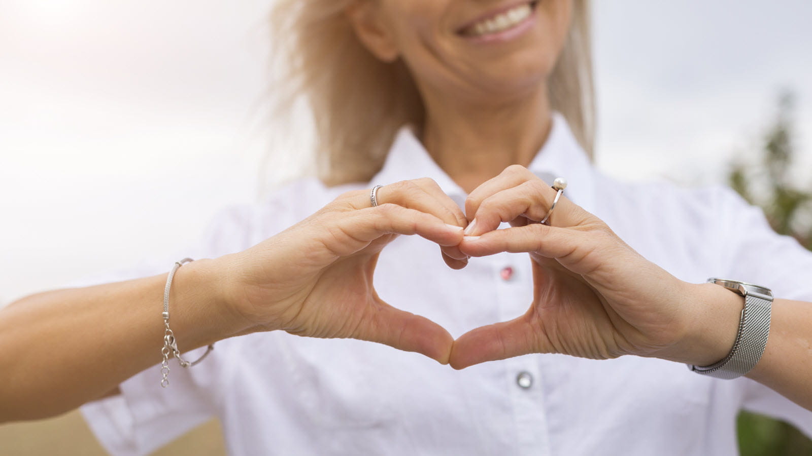 smiling woman forms a heart with her hands