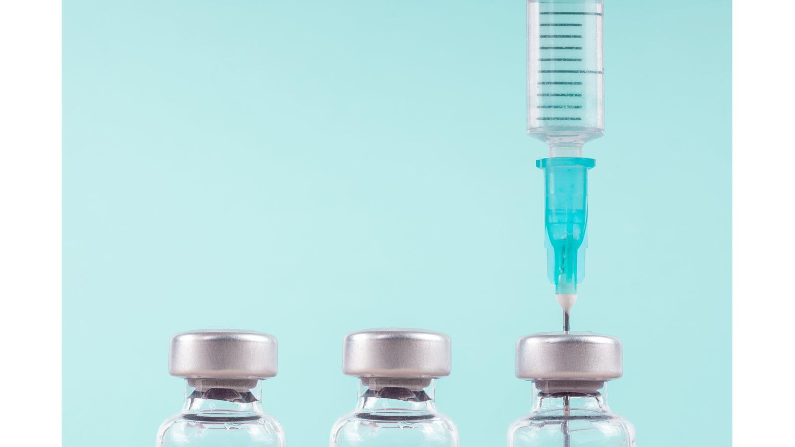 flu vaccine syringe going into a bottle on a blue background