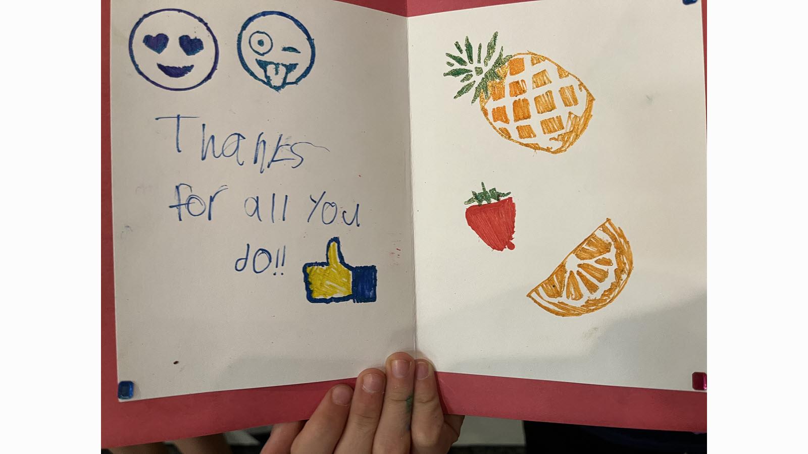 A child's hand-drawn card that says "Thanks for all you do" with images of a pineapple and other fruit
