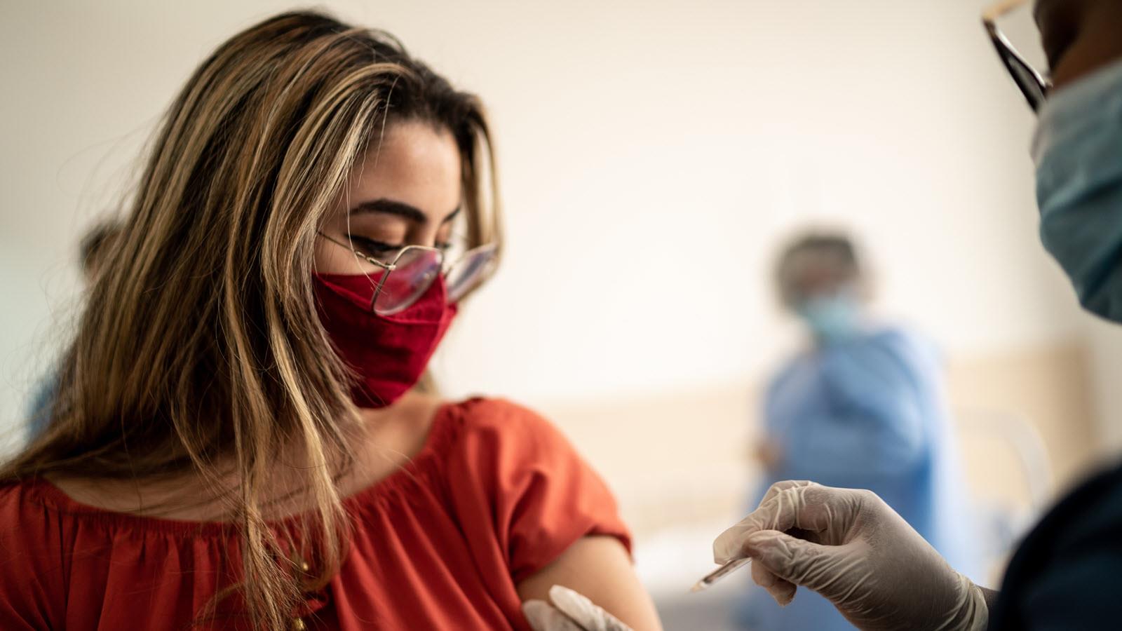 woman wearing a mask receives a flu shot