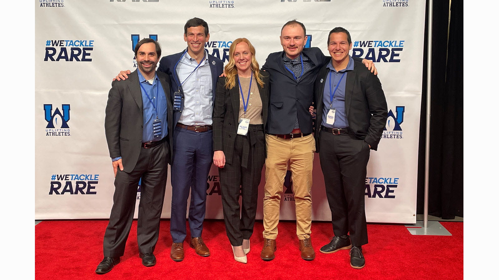 Dr. David Fagjenbaum, second from left, and Melanie Mumau (center) celebrating at the 2023 Uplifting Athletes Young Investigator Draft at Lincoln Financial Field. 