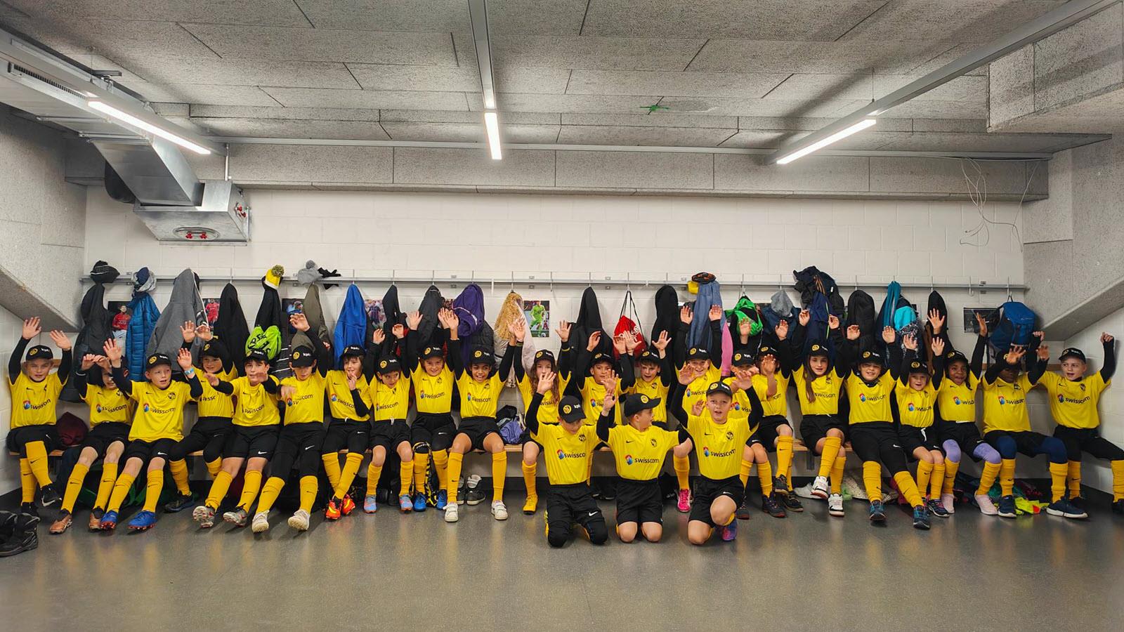 Children raise their hands in the air in the locker room.