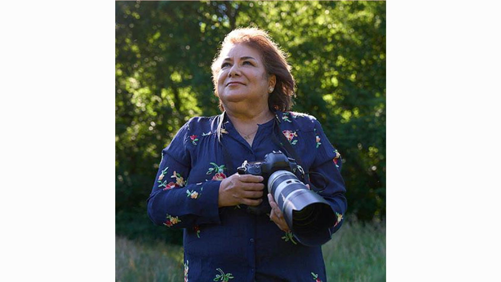 Alice Drennon, a primary immunodeficiency patient, outdoors holding a camera with a long lens