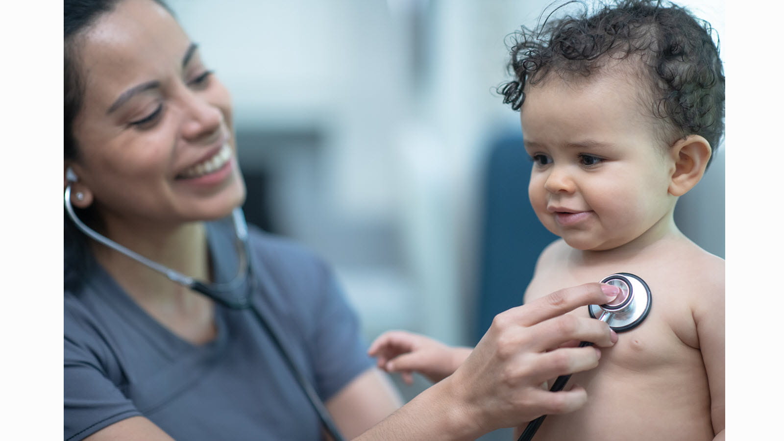 Smiling doctor listens to baby's heart